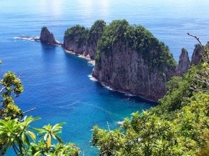 an outcrop of rocks walking in to the glistening American Samoan sea