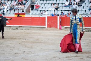 A Matador in a bull fight with red cape