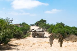 a tank in israel with two soldiers ahead