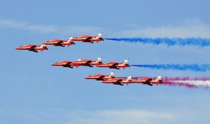 The Red Arrows flying in Formation with blue smoke trails