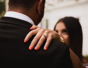 a diamond ring on a woman's finger, shown over her partners shoulder