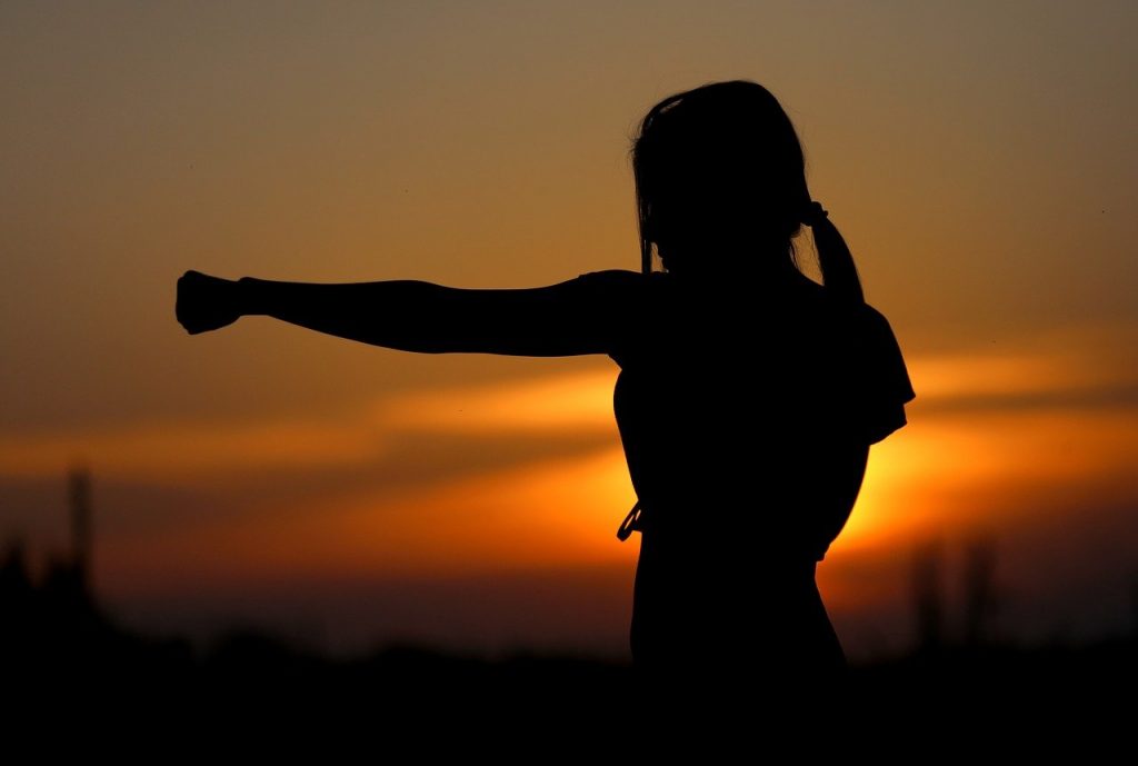 woman practicing karate with a sunset background