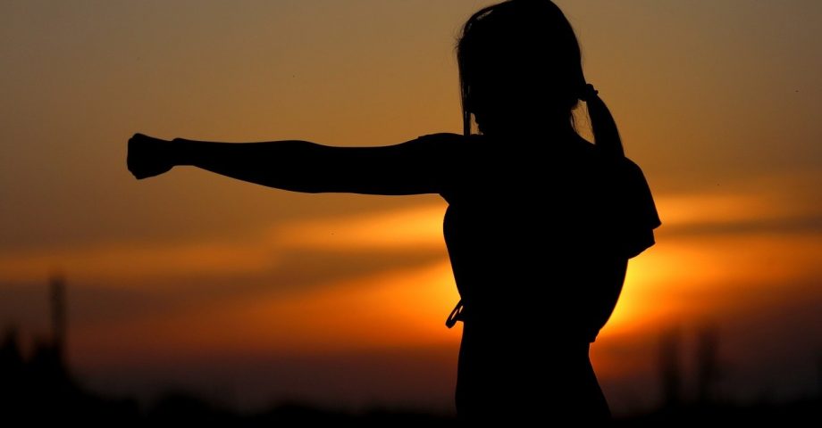 woman practicing karate with a sunset background