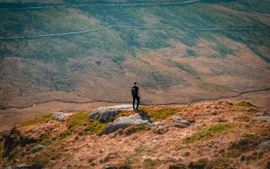 a man standing on top of a lush greenSnowdonia hillside